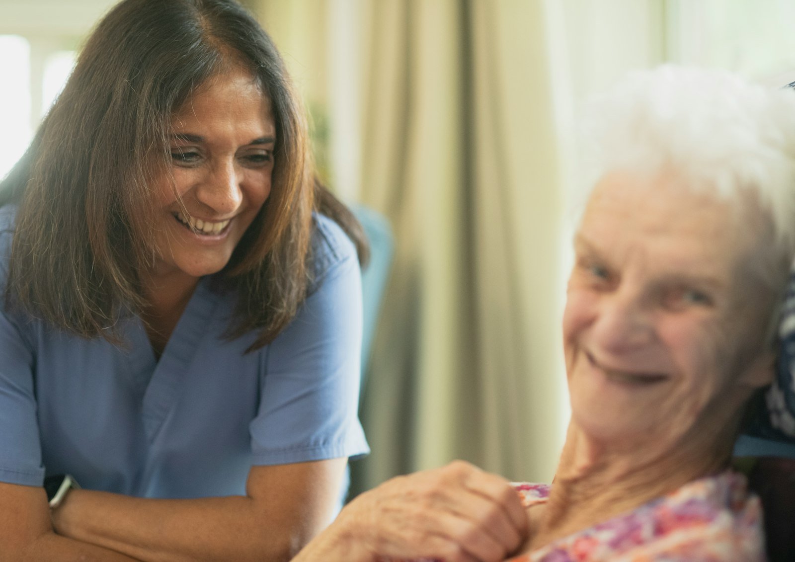 Nurse smiling with an elderly patient in a care room